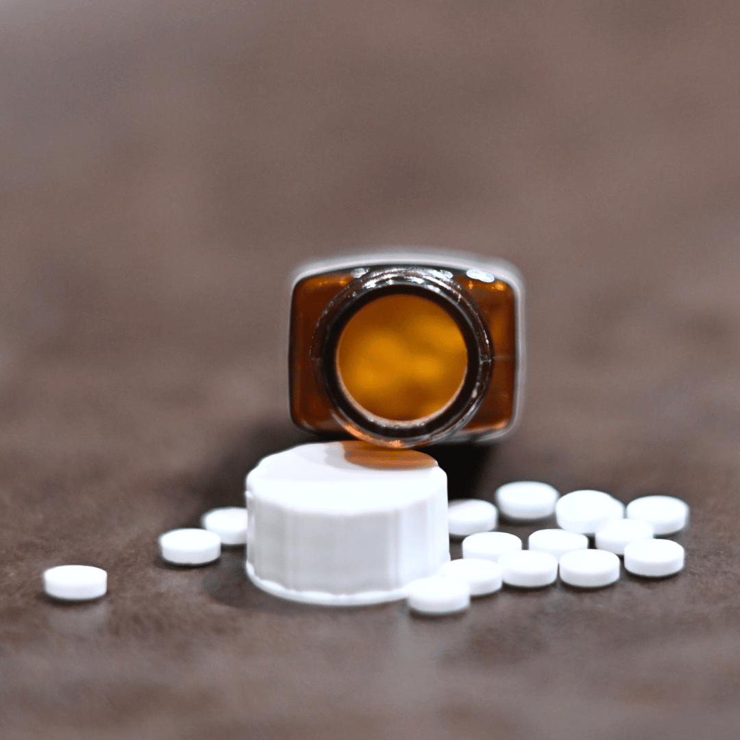 Bottle of homeopathic tablets. Lid of bottle is open showing contents of bottle