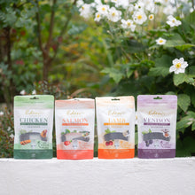 Eden Sausage Treats: chicken, salmon, lamb, and venison sausages in colorful packaging near flowers.