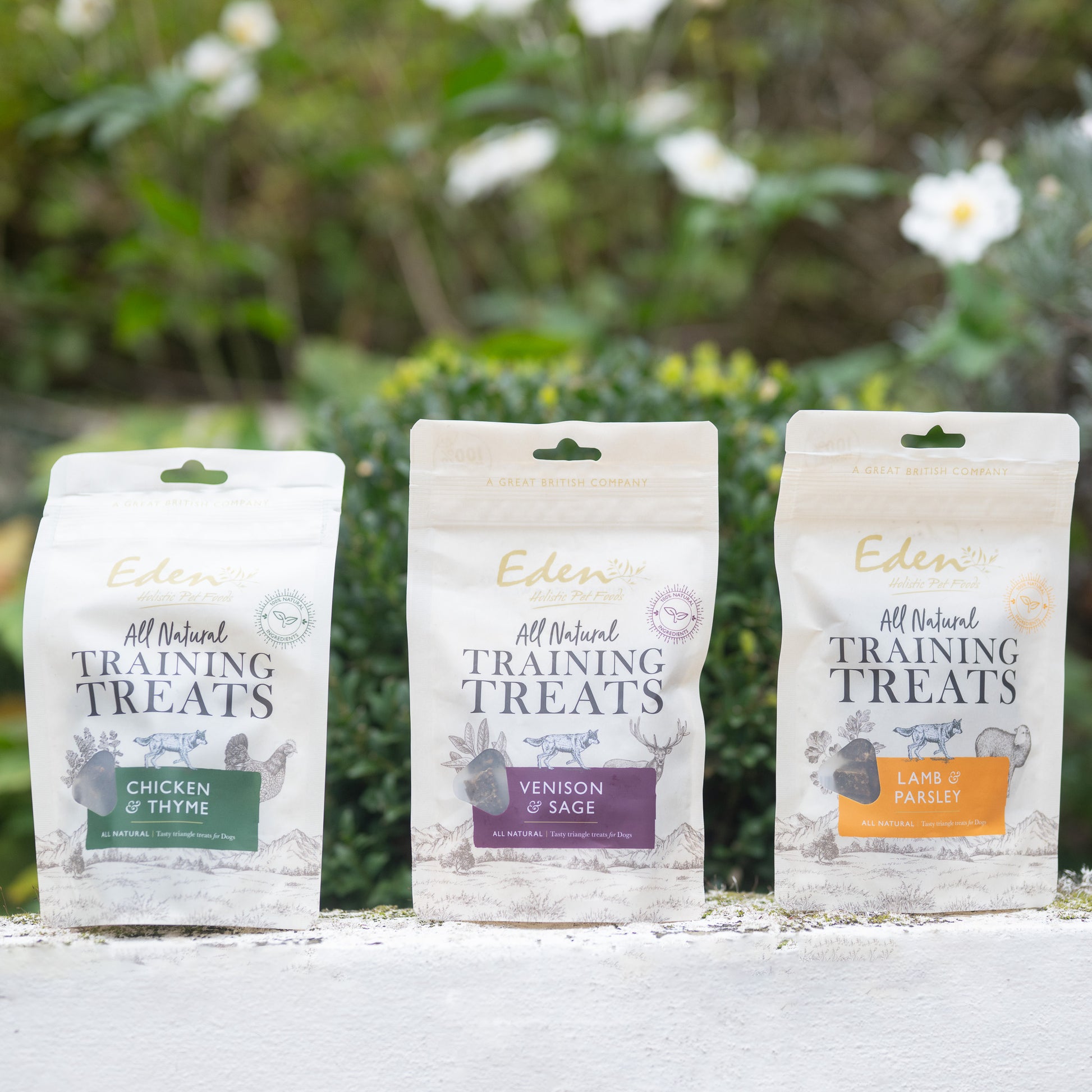 Eden Training Treats packaging for Chicken & Thyme, Venison & Sage, and Lamb & Parsley, displayed outdoors.