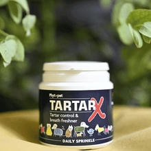 Tartar X tartar control and breath freshener for dogs container with green leaves in the background