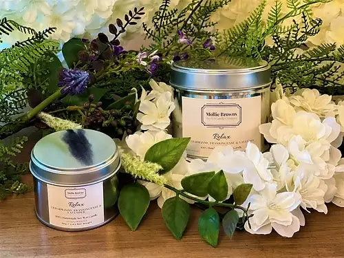 Mollie Browns pet friendly scented candles surrounded by flowers and greenery, made from natural soy wax and essential oils.